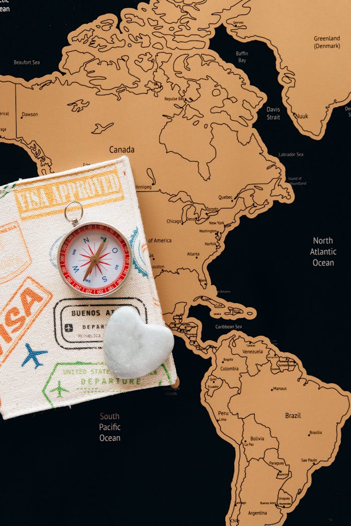 Flat lay photo of a map, passport, and compass, symbolizing travel and adventure.
